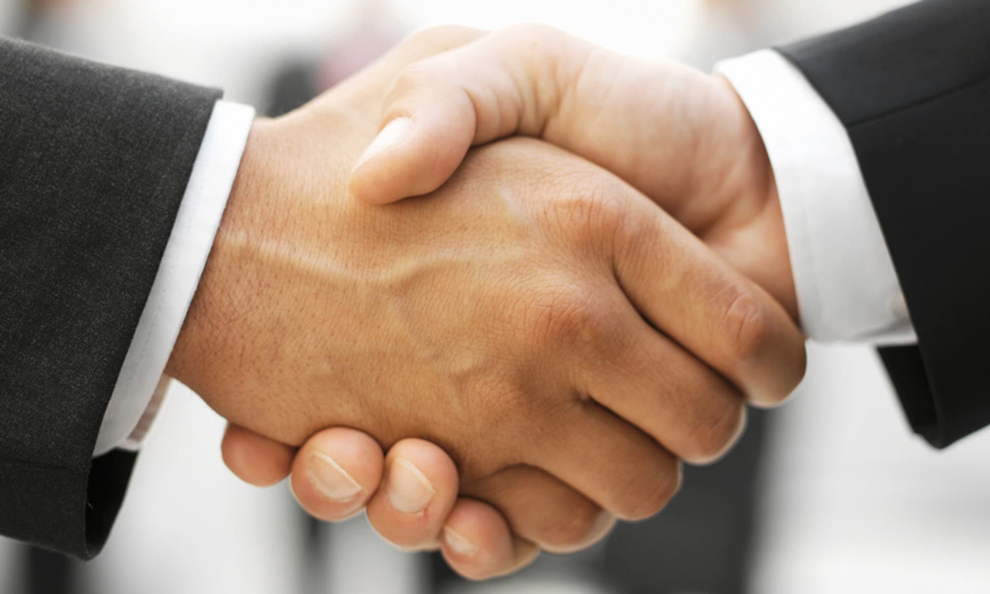 Two people in business suits shaking hands