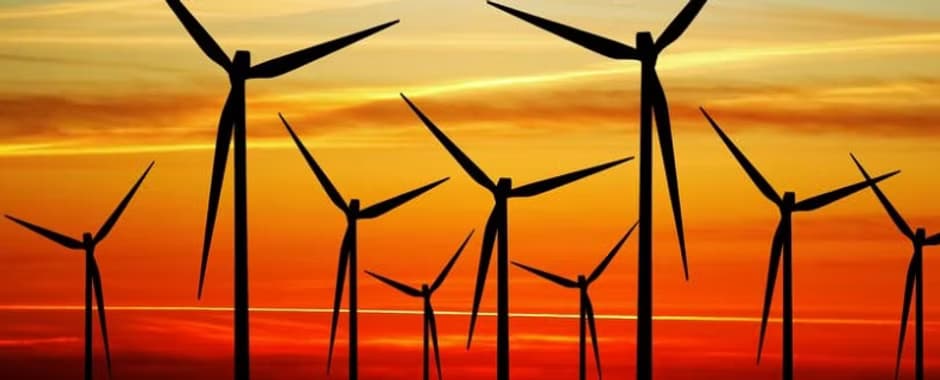 Wind turbines silhouetted against an orange sunset